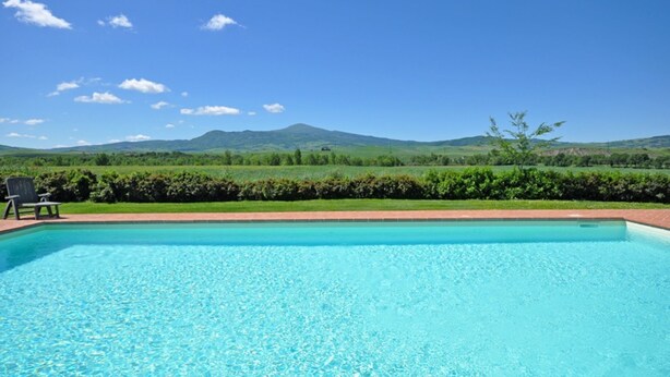 A swimming pool with clear blue water, surrounded by a brick border, and a view of green hills and a clear sky in the background. - Cosy apartment for 4 guests with WIFI, pool, TV and panoramic view, close to Montepulciano (Monticchiello)