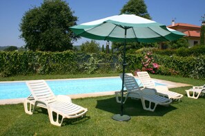 A swimming pool with lounge chairs and an umbrella.