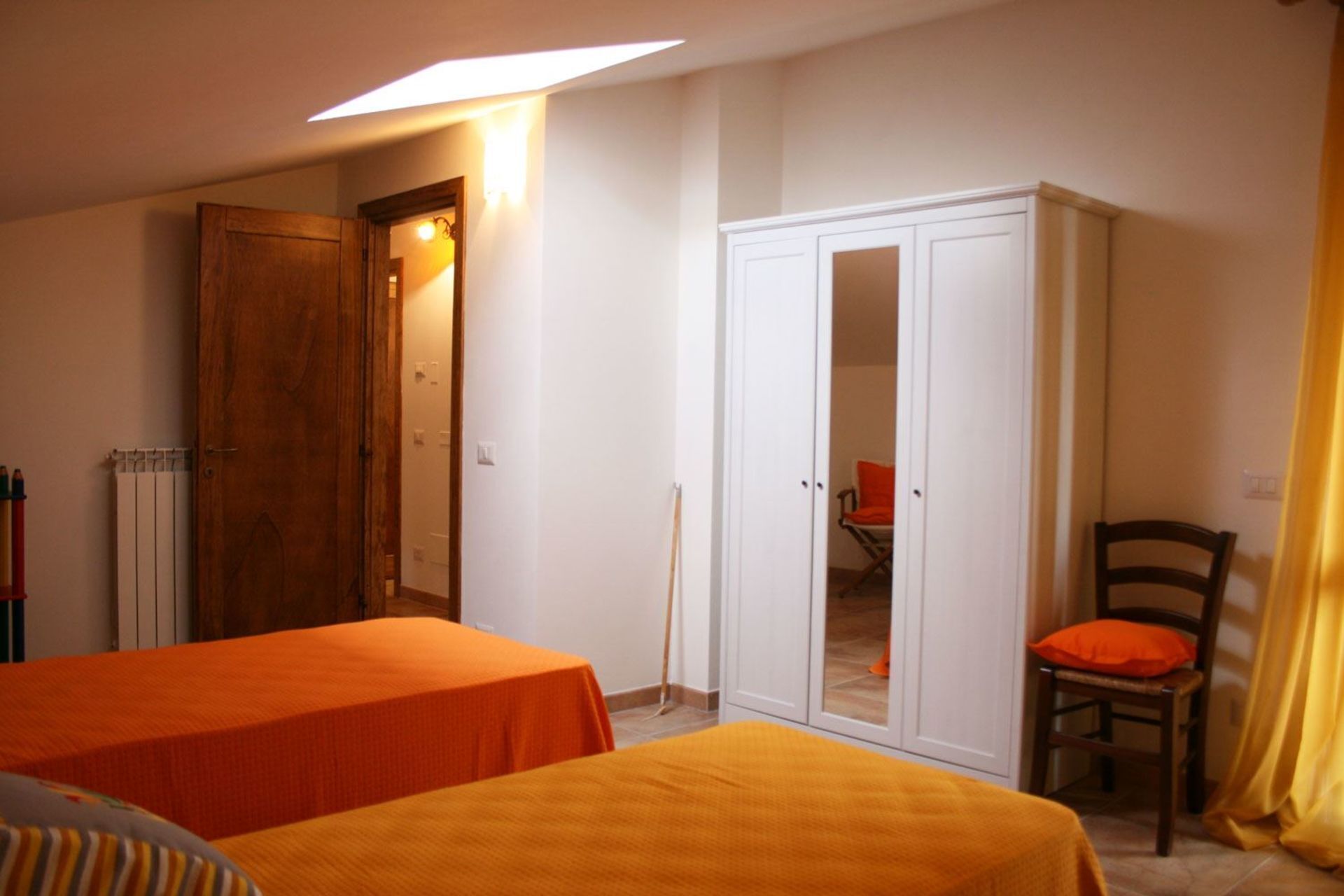 A room with two beds, a wardrobe, a chair, and a radiator.