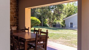 An outdoor patio with a wooden table and chairs, a stone wall, and a view of a garden and house. - Villa Morandi - Holiday Country Villa with swimming pool in Loro Ciuffenna, Tuscany (Loro Ciuffenna)