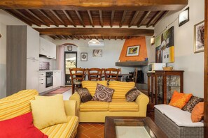 Una sala de estar acogedora con un conjunto de sofás, una mesa de comedor y una cocina visible a través de una puerta abierta.