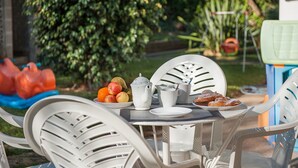 A table set outdoors with a fruit bowl, teapot, and cups.