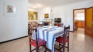A dining area with a table set for four, a television, and a kitchen visible in the background.