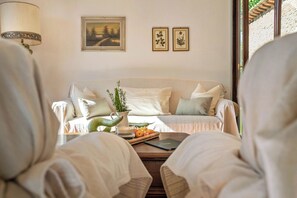 A cozy room with a sofa, a lamp, and framed botanical prints on the wall.