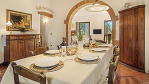 A dining area with a long table set for a meal, wooden chairs, a chandelier, and a rustic brick archway. - Wonderful private villa for 8 guests with WIFI, private pool, A/C, TV and patio (Palaia)