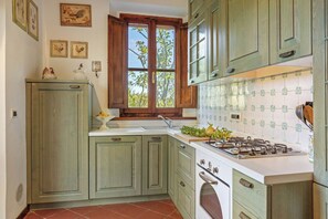 Een keuken met een fornuis, spoelbak en groene kastjes.