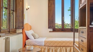 A bedroom with two beds, a wooden dresser, a small table, and a window with a view of greenery. - Wonderful private villa for 8 guests with WIFI, private pool, A/C, TV and patio (Palaia)
