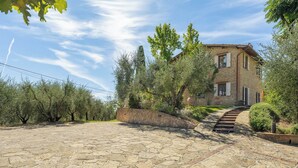 A stone-paved courtyard leading to a two-story house with a brick facade, surrounded by olive trees and a stone wall. - Wonderful private villa for 8 guests with WIFI, private pool, A/C, TV and patio (Palaia)