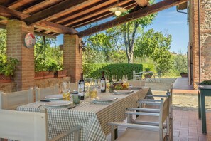 An outdoor dining area with a checkered tablecloth, wine glasses, and a bottle of wine.