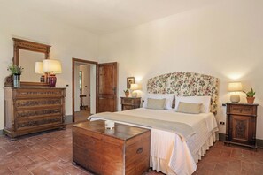 A bedroom with a large bed, wooden dresser, and a mirror.