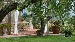 Eine Terrasse im Freien mit Tisch und Stühlen, umgeben von Blumentöpfen und einer Steinmauer.