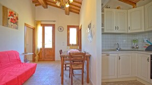 A kitchen with white cabinets, a dining table with chairs, a red sofa, and a chandelier. - Stunning private villa with private pool, WIFI, A/C, TV, terrace, pets allowed and panoramic view (Fontanella)