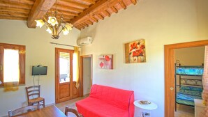 A cozy room with a wooden ceiling, a red sofa, a dining table with chairs, a TV, and a painting on the wall. - Stunning private villa with private pool, WIFI, A/C, TV, terrace, pets allowed and panoramic view (Fontanella)