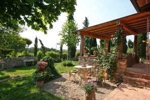 Ein Patio mit Steinmauer, Kübelpflanzen und einer Holzpergola.