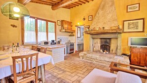 A rustic kitchen with a stone fireplace, wooden beams, and a dining area with a table set for a meal. - Stunning private villa with private pool, WIFI, TV, patio and panoramic view, close to San Gimig... (Sciano)