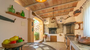 A rustic kitchen with a brick fireplace, wooden shelves, and a bowl of fruit on a table. - CA SA NINA - Villa with private pool in Inca. Free WiFi (Inca)