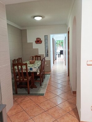 Un couloir mène à une salle à manger où se trouvent une table, des chaises et un panier.