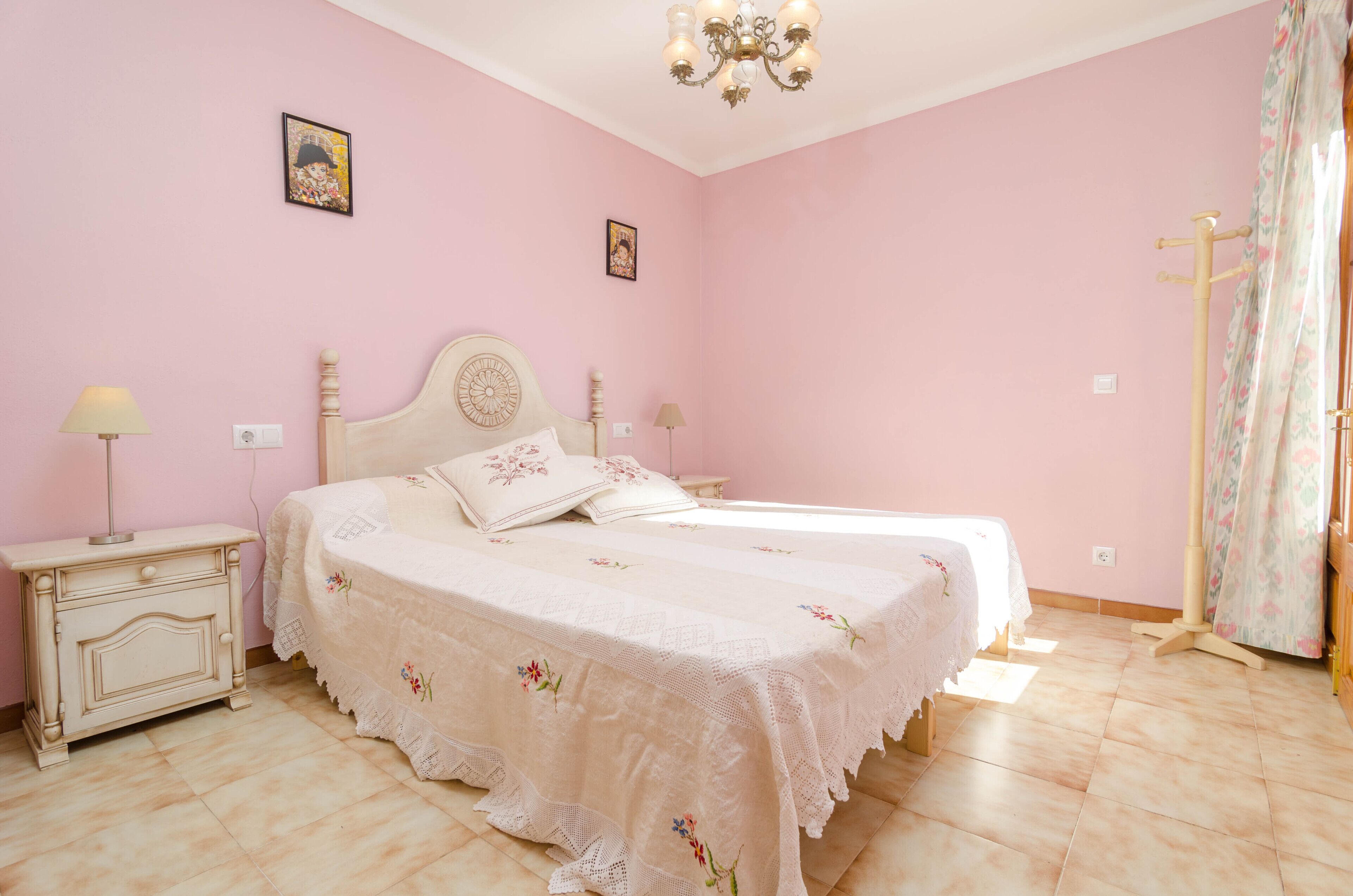 Une chambre à coucher avec un lit double, une table de chevet, une lampe et un lustre.