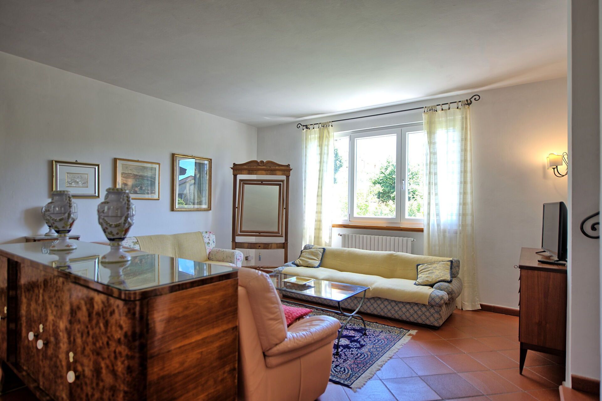 Una sala de estar con un sofá, una mesa de centro, un mueble de madera y una televisión.