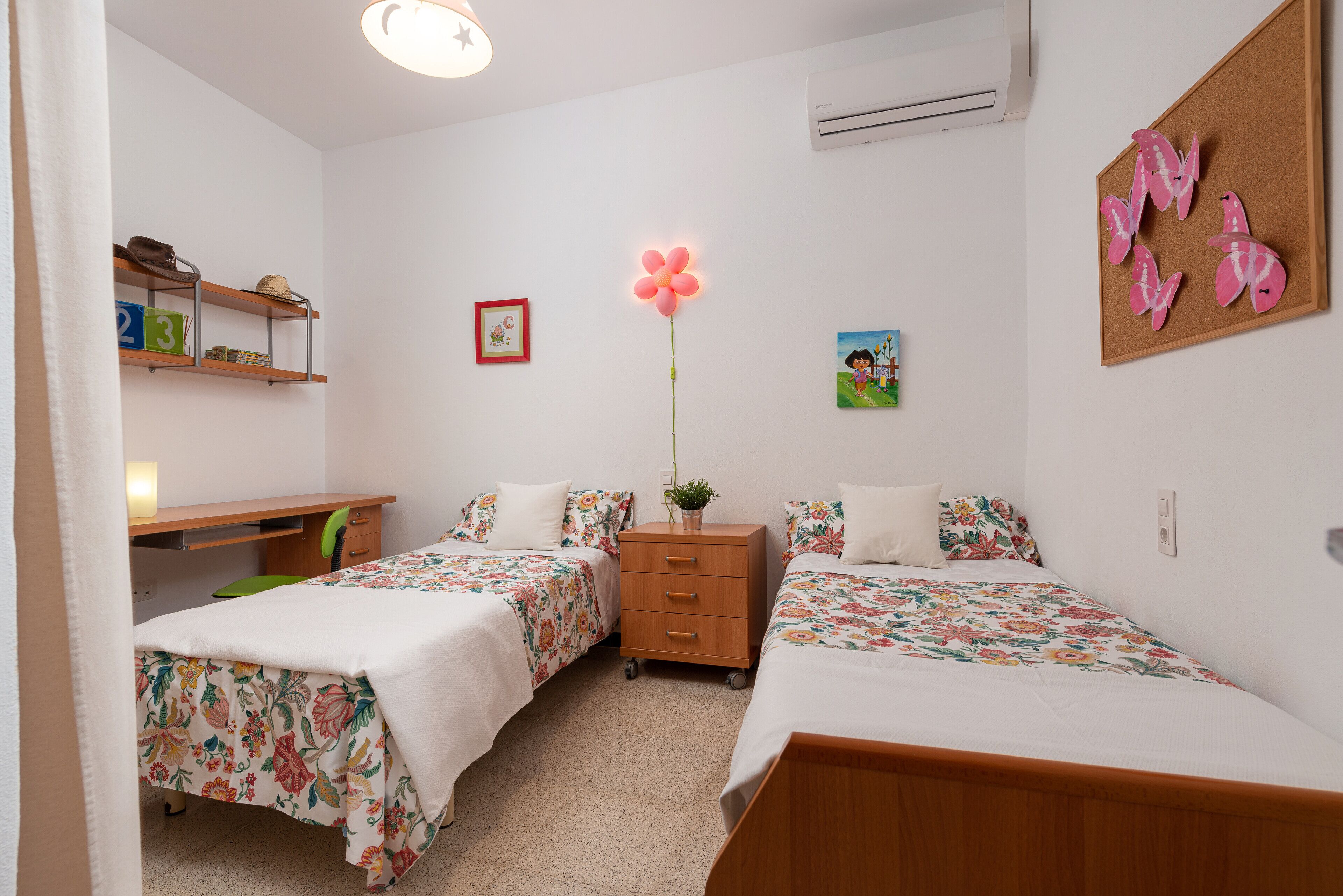 Een slaapkamer met twee bedden, een bureau en een dressoir.