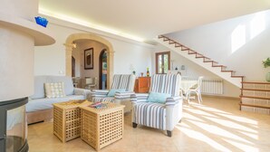 A spacious living room with a sofa, striped armchairs, a coffee table, and a staircase leading to an upper floor. - PLETA DE BONANY - Villa with private pool in Vilafranca De Bonany. Free WiFi (Vilafranca de Bonany)