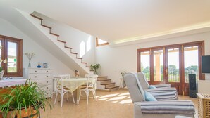A spacious living area with a staircase, a dining table with chairs, a sofa, and a television. - PLETA DE BONANY - Villa with private pool in Vilafranca De Bonany. Free WiFi (Vilafranca de Bonany)