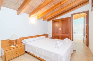 A bedroom with a wooden bed, a nightstand, a lamp, and a wardrobe.