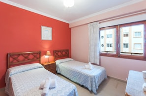 A room with two beds, a nightstand with a lamp, a window with curtains, and a framed picture on the wall. - SIRENASea view apartment in Moraira - Free Wifi (Moraira)