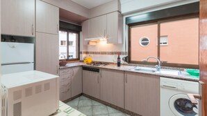 Cocina compacta con lavavajillas integrado, estufa y ventana con vistas al exterior.