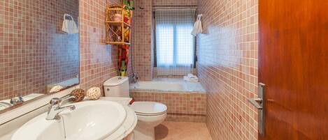 Een badkamer met een wastafel, toilet en bad.