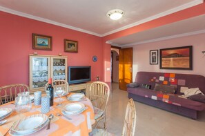 A dining area with a table set for four, a television, and a sofa in the background. - SIRENASea view apartment in Moraira - Free Wifi (Moraira)