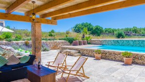 Un espacio al aire libre techado con piscina, paredes de piedra y asientos.