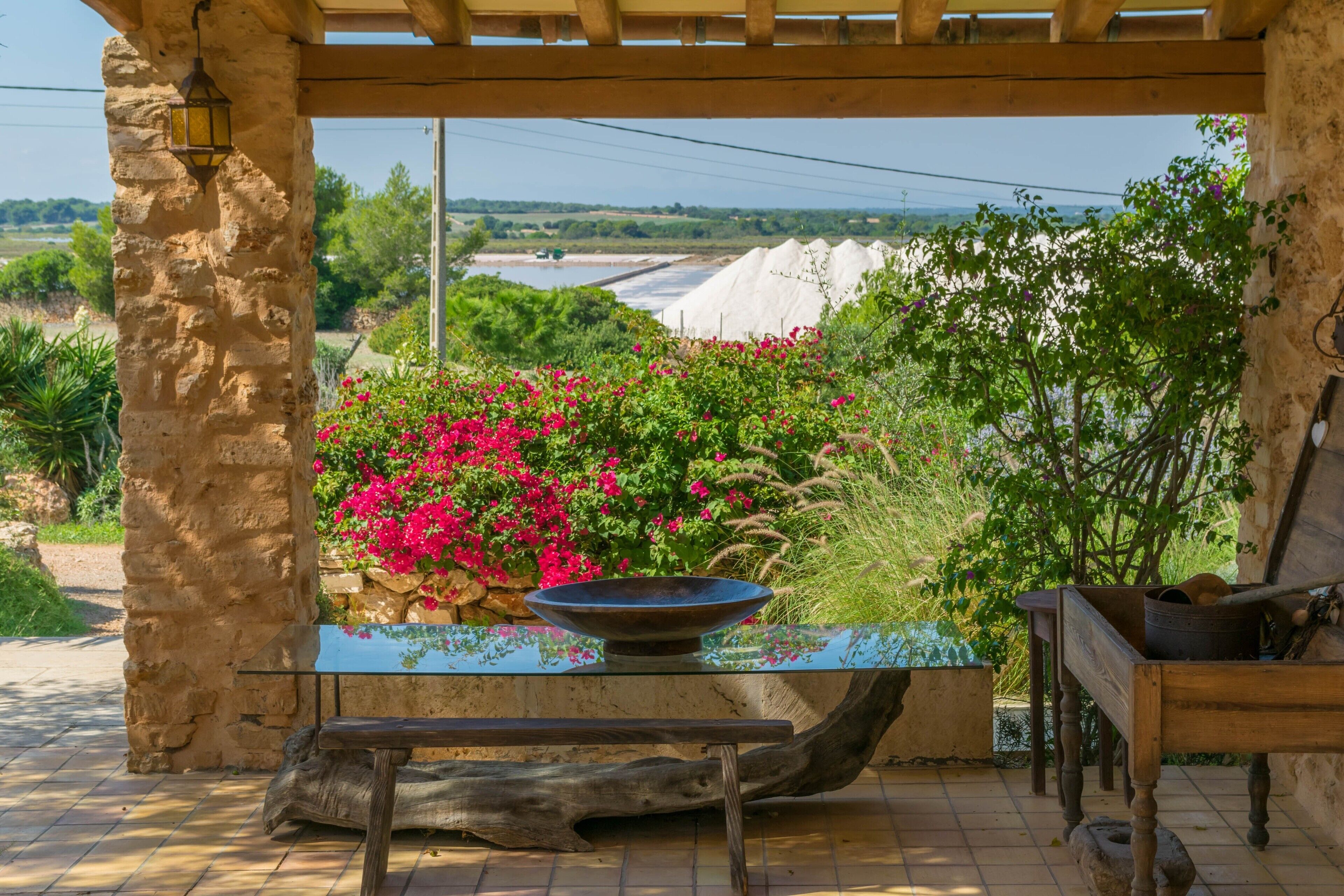 Zona relax esterna in stile rustico con un pilastro in pietra, un tavolo in legno e una panca semplice.