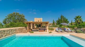 A swimming pool with lounge chairs and a stone structure.