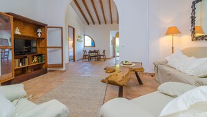 A spacious living room with a wooden entertainment unit, a sofa, a coffee table, and a dining area with chairs and a table. - TORRE MARINA - Villa with private pool in Sa Ràpita. Free WiFi (Sa Ràpita)