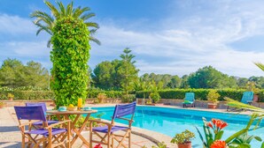 A pool area with a wooden table and chairs, surrounded by potted plants and flowers. - TORRE MARINA - Villa with private pool in Sa Ràpita. Free WiFi (Sa Ràpita)