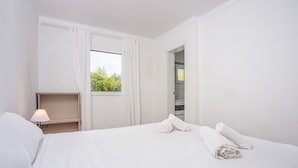Une chambre d’hôtel avec un lit, une table de chevet avec une lampe, une fenêtre avec des rideaux et une vue sur la verdure.