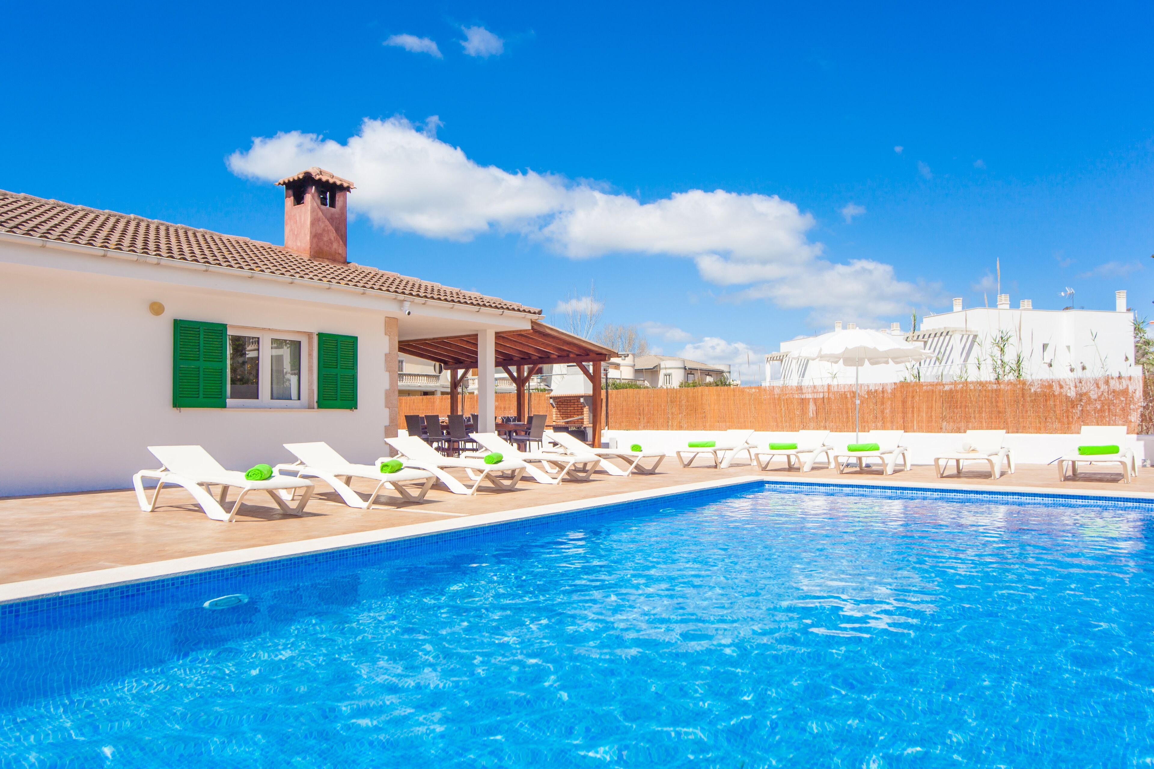 A swimming pool with lounge chairs and a covered seating area.