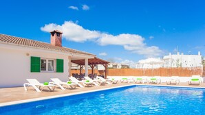 Une piscine avec des chaises longues et un espace salon abrité.
