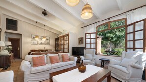 A spacious living room with a white sofa set, a wooden coffee table, and a large window offering a view of greenery. - SA MARJAL - Chalet with private pool in MURO. Free WiFi (Muro)