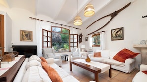 A spacious living room with white furniture, large windows, and a rustic decor including a large wooden spoon hanging on the wall. - SA MARJAL - Chalet with private pool in MURO. Free WiFi (Muro)