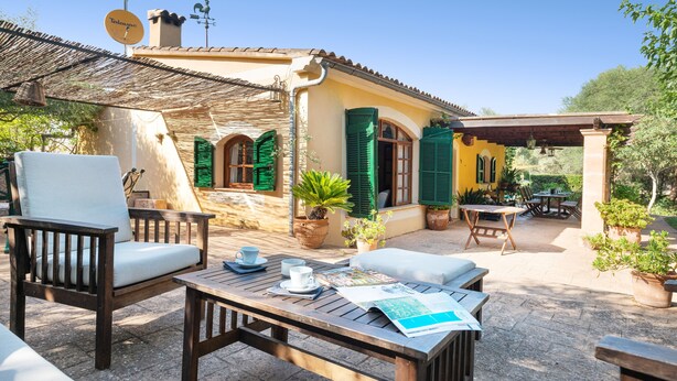 A patio with outdoor furniture, a table with a magazine, and a building with green shutters and a satellite dish. - SA MARJAL - Chalet with private pool in MURO. Free WiFi (Muro)
