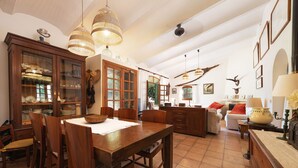 A spacious dining area with wooden furniture, a large cabinet with glass doors, and hanging wicker lamps. - SA MARJAL - Chalet with private pool in MURO. Free WiFi (Muro)