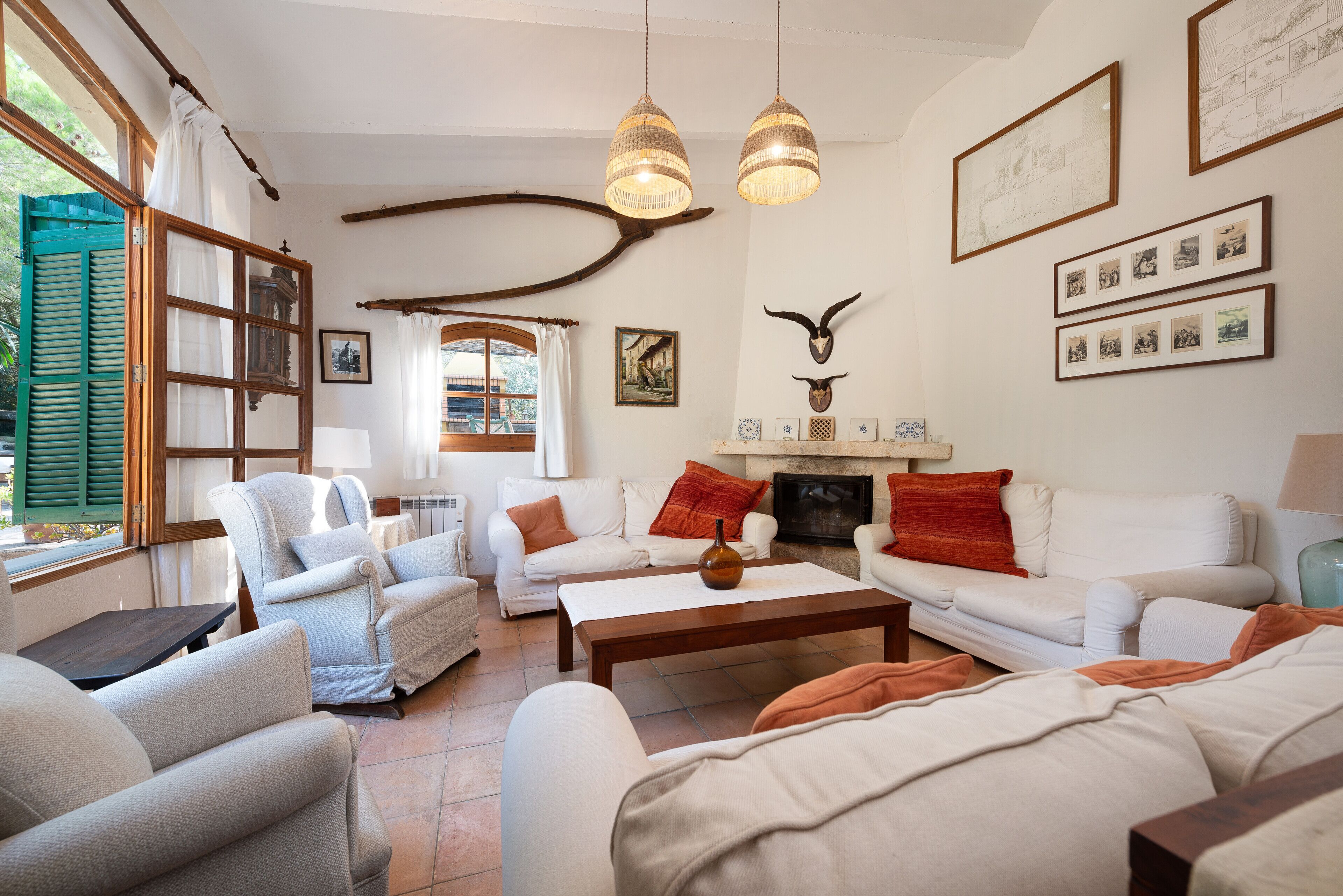 A cozy living room with a fireplace, comfortable seating, and a large window with shutters.