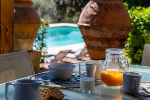 Une table de petit-déjeuner avec une carafe de jus d’orange, un bol, un verre de lait et une tasse.