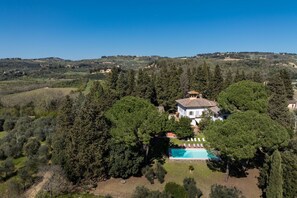 Une villa entourée d’une végétation luxuriante, dotée d’une piscine et offrant une vue sur la campagne.