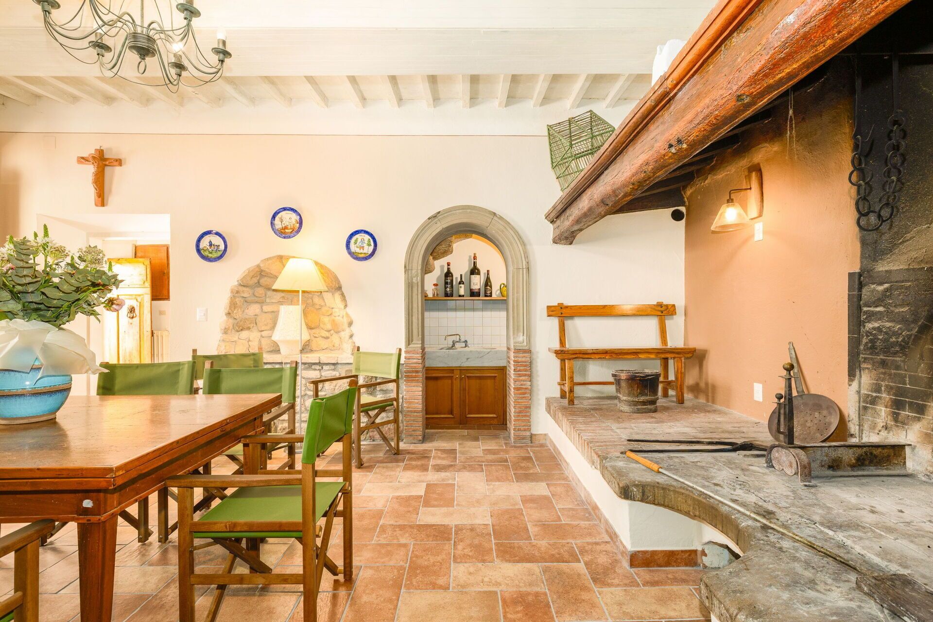 A dining area with a stone fireplace, wooden furniture, and a cross on the wall.