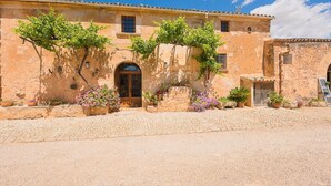 Un bâtiment historique doté d’une façade en pierre, d’une entrée en arc de cercle et de plantes en pot.