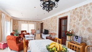 Una sala de estar con una mesa de comedor, un televisor y una pared de piedra.