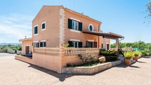 Una casa de dos pisos con balcón, escalones de piedra y plantas en macetas.